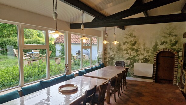 A dining area with a long table, benches, and hanging lights. - Le Cottage: close to the forest and Baie de Somme. Ideal for families (Machy)