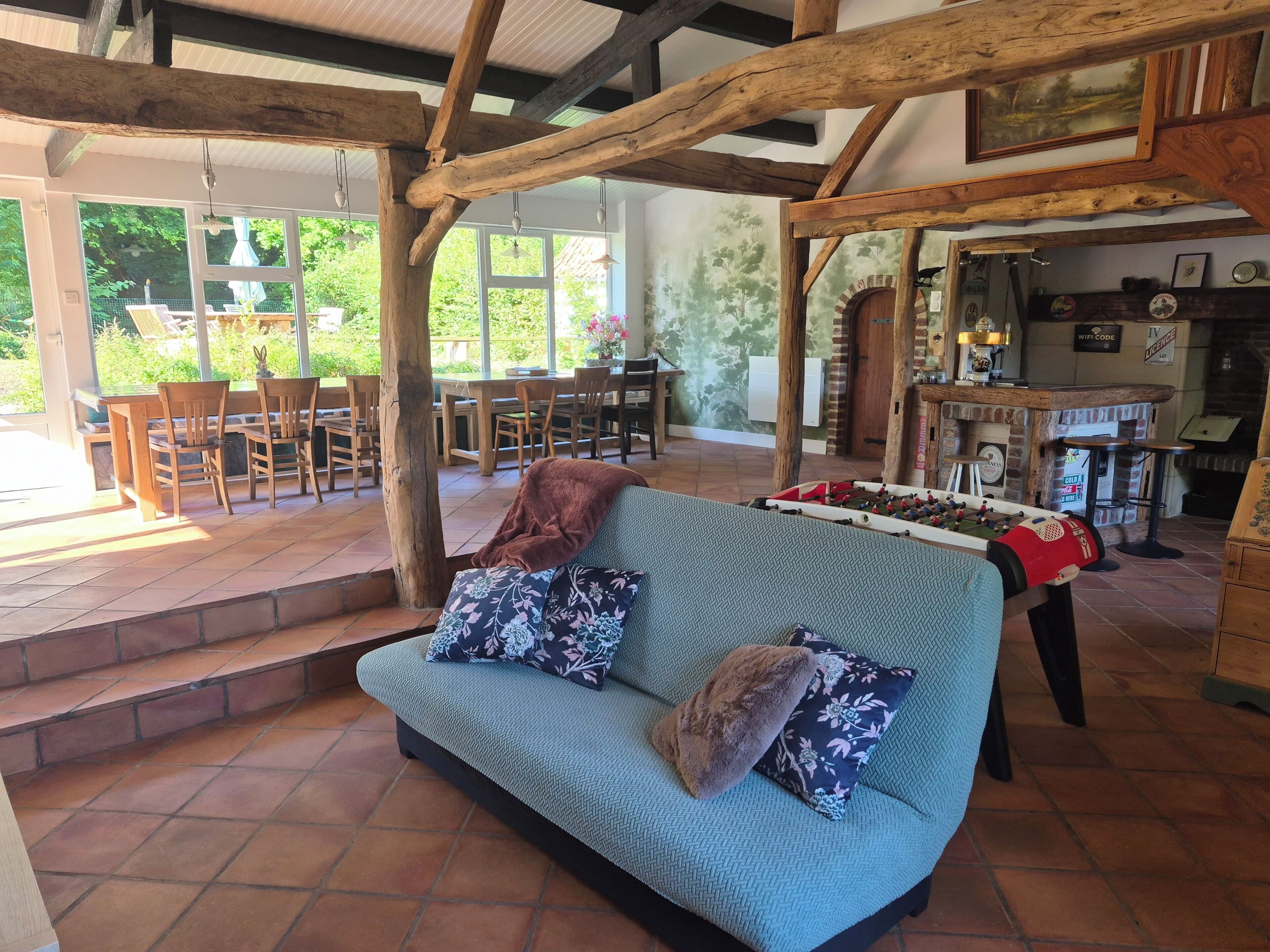 Une pièce chaleureuse avec un canapé, une table de baby-foot et un plafond en bois rustique.