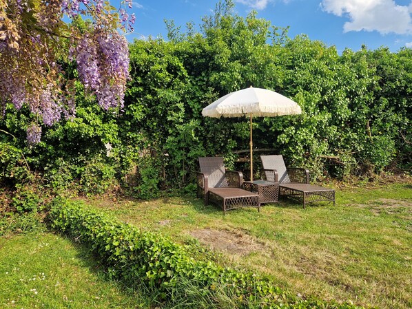 An outdoor seating area with wicker furniture and a white umbrella. - Le Cottage: close to the forest and Baie de Somme. Ideal for families (Machy)
