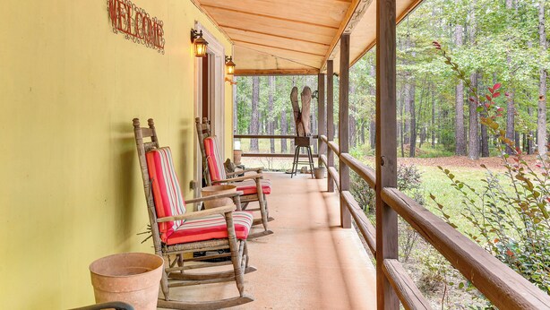 A porch with rocking chairs, a welcome sign, and a view of a forest. - Forested Family Hideaway Near Lake Sinclair! (Eatonton)