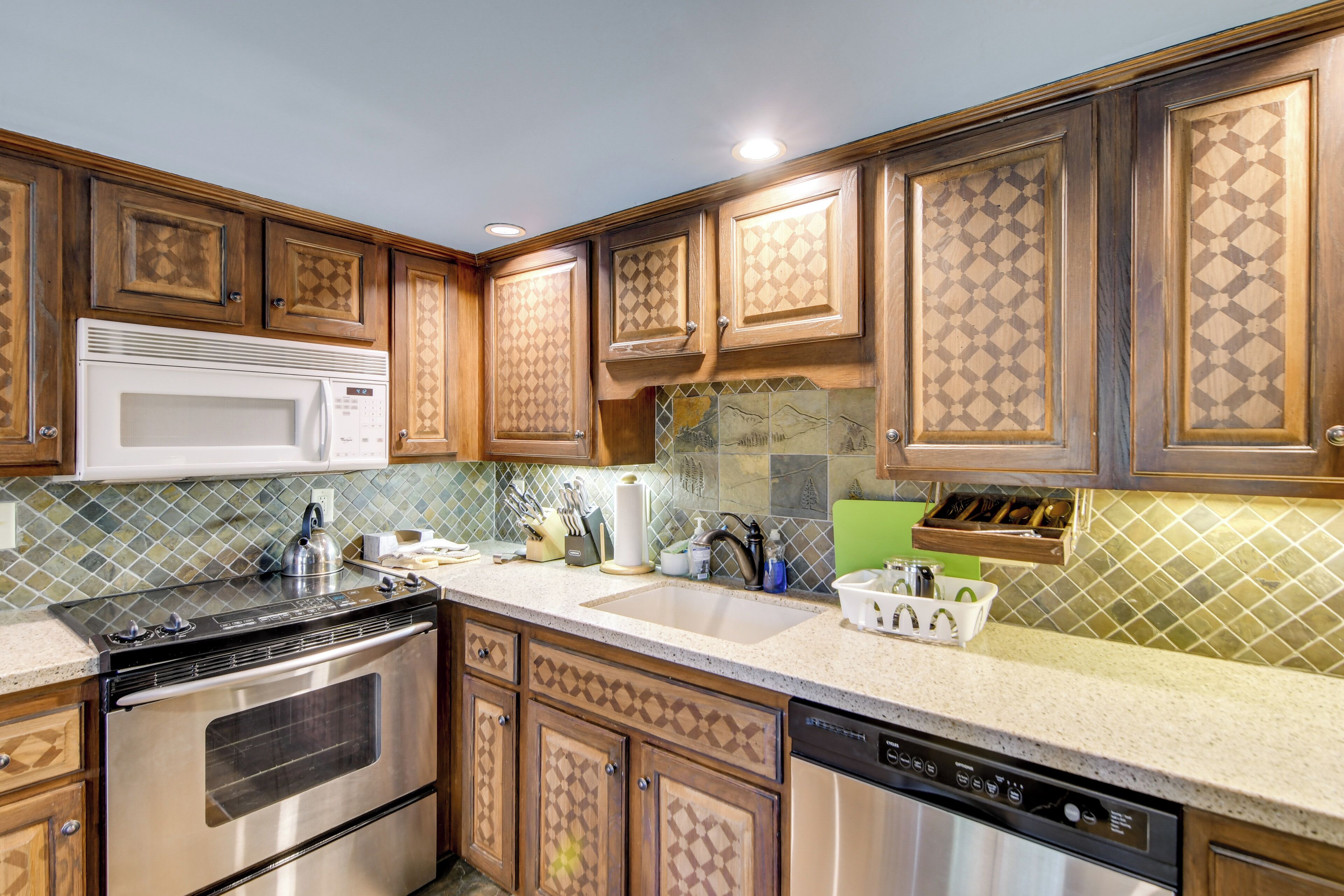A kitchen with wooden cabinets, a stainless steel oven, a microwave, and a dishwasher.