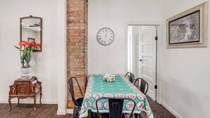 Un comedor con pared de ladrillo, un reloj y una mesa con sillas.