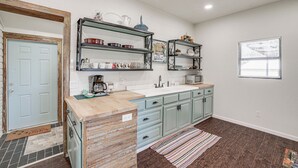 Una cocina con armarios azul claro, encimera de madera y alfombra a rayas.