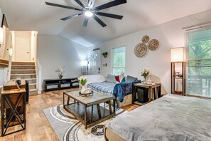 A spacious living room with a high ceiling fan, a staircase, a sofa, a coffee table, and a large window with blinds. - Easy I-20 Access to ATL: Suburban Retreat w/ Yard (Douglasville)