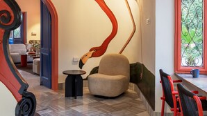 Um interior moderno com uma escultura singular, uma escadaria curva e uma área de refeições com cadeiras vermelhas.