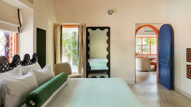 Quarto de hotel com cama, uma cadeira, escrivaninha e vista para o exterior.