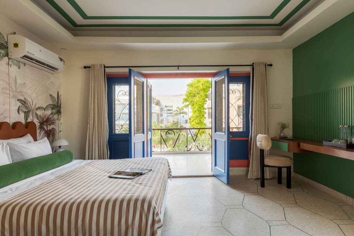 A hotel room with a bed, a desk, and a view of the outside.