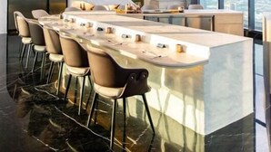 A modern kitchen with a central island, bar stools, and a large window providing a city view.