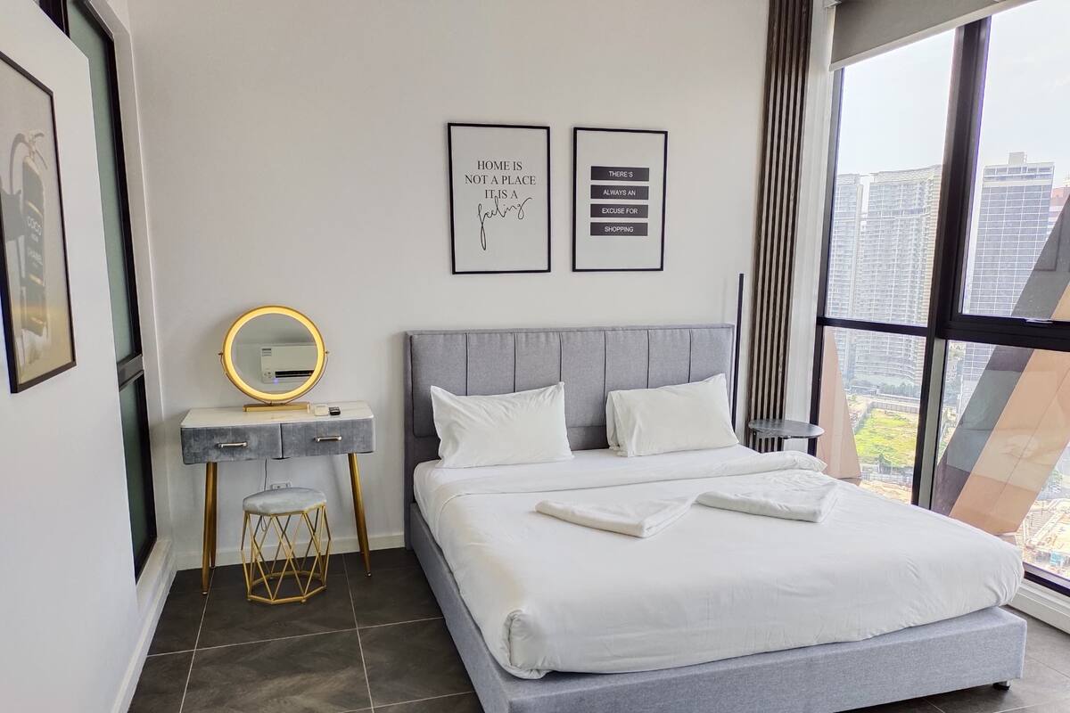 Une chambre d’hôtel moderne avec un grand lit, une coiffeuse avec un miroir et deux citations inspirantes encadrées au mur.