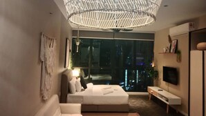 A modern bedroom with a large bed, a TV, and a city view through the window.