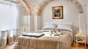 Un dormitorio con cama, mesita de noche, cuadro enmarcado en la pared y techo de ladrillo abovedado.