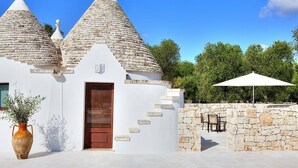Un edificio con techos cónicos, una puerta de madera y un muro de piedra con escalones que llevan a un patio.