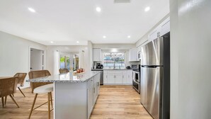 A modern kitchen with white cabinets, stainless steel appliances, and a central island.