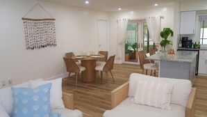 A modern living room with a dining area, a kitchen, and a balcony.