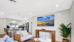 A modern living room with a sofa, a coffee table, and a dining area.