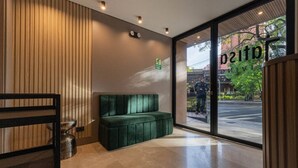 Ein modernes Interieur mit einer gepolsterten grünen Bank, einer Wand aus Holzlatten und einer großen Glasdoor, die nach draußen führt.