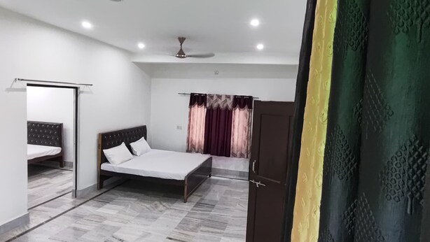 A bedroom with a bed, a wardrobe, a ceiling fan, and a large mirror. - Shree Shyam Paying Guest House (Varanasi)