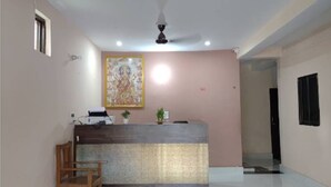A reception area with a reception desk, a ceiling fan, and a framed artwork on the wall. - Shree Shyam Paying Guest House (Varanasi)