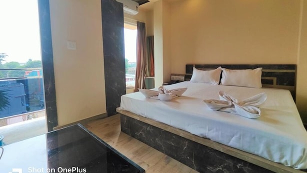 A hotel room with a large bed, a small table, and a view of the outdoors. - Hotel Sea Wood (Digha)