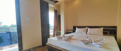 Habitación de hotel con una cama grande, una mesita y vistas al exterior.