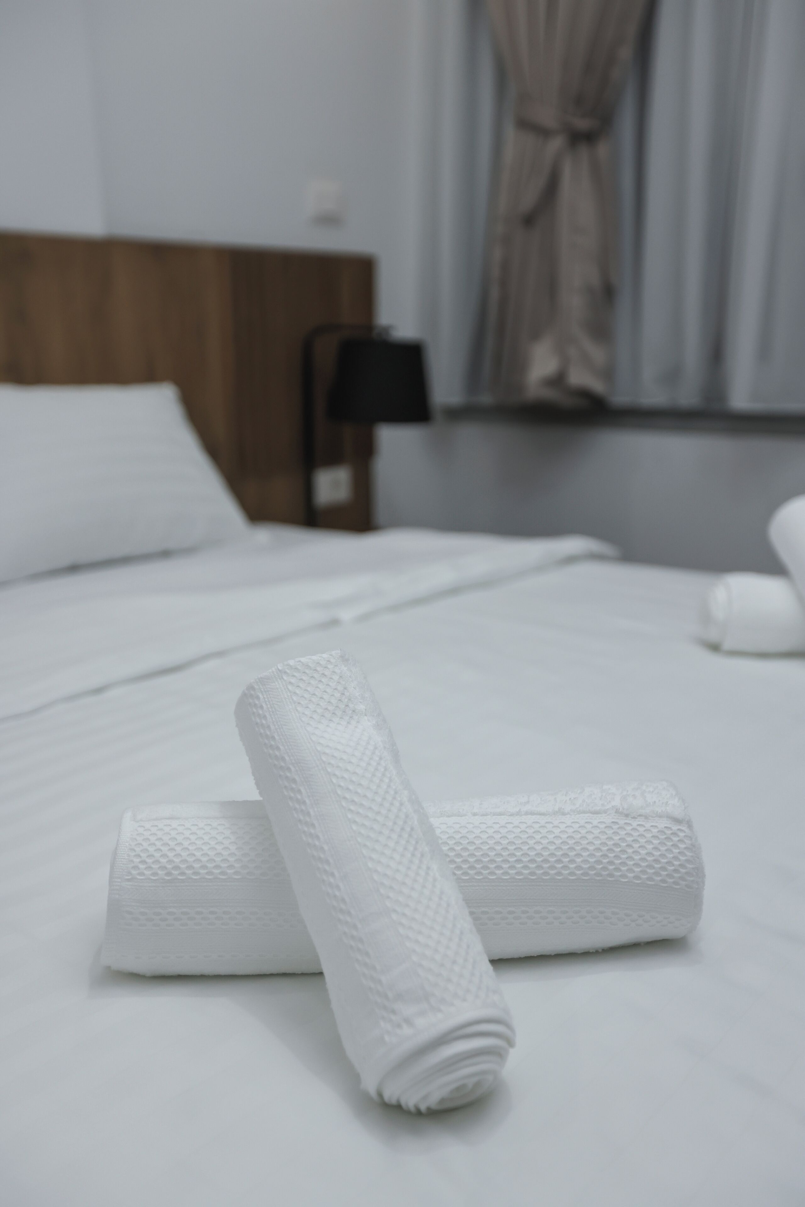 A neatly made bed with white linens and a wooden headboard.