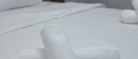 A neatly made bed with white linens and a wooden headboard.