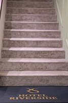 Una escalera alfombrada que conduce a una habitación con un letrero que dice 'HOTEL RIVERSIDE'.
