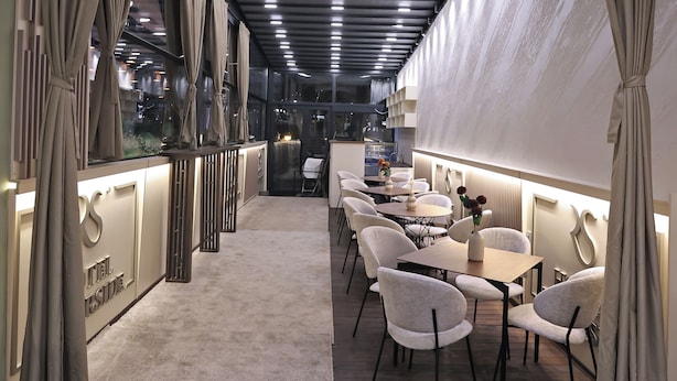 A hotel corridor with a carpeted floor, a reception desk, and seating areas. - Hotel Riverside (Skopje)