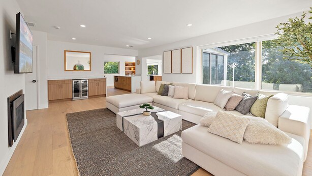 A modern living room with a large sectional sofa, a marble coffee table, and a view of the outdoors through large windows. - Sunlit & Spacious Seattle Home near Space Needle (Seattle)