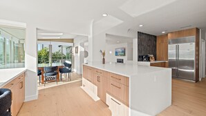 A modern kitchen with a large island, wooden cabinets, and a stainless steel refrigerator. - Sunlit & Spacious Seattle Home near Space Needle (Seattle)