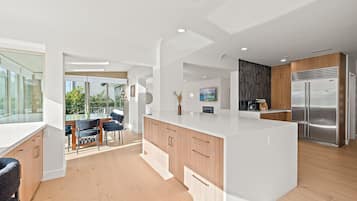 A modern kitchen with a large island, wooden cabinets, and a stainless steel refrigerator.