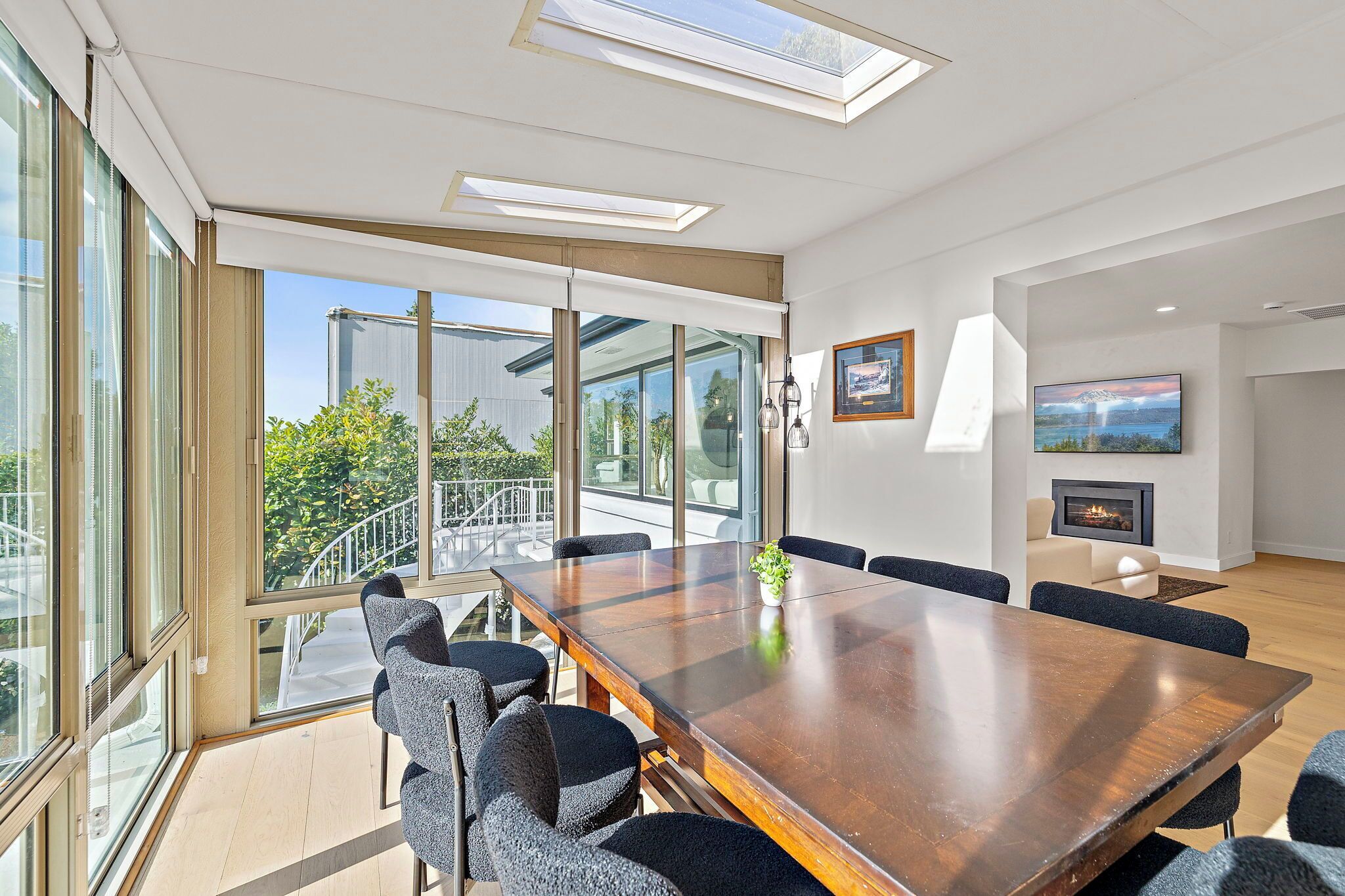 A modern conference room with a large wooden table, comfortable chairs, and large windows offering a view of the outdoors.