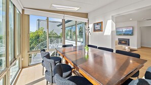 A modern conference room with a large wooden table, comfortable chairs, and large windows offering a view of the outdoors. - Sunlit & Spacious Seattle Home near Space Needle (Seattle)