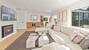 A modern living room with a fireplace, a large TV, and a sofa. - Sunlit & Spacious Seattle Home near Space Needle (Seattle)
