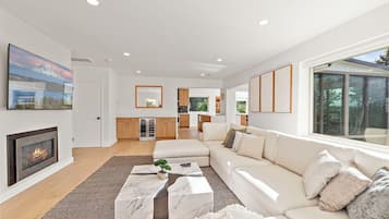 A modern living room with a fireplace, a large TV, and a sofa.