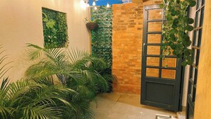 Un pasillo estrecho con suelo de baldosas, pared de ladrillo y una puerta con ventanilla.