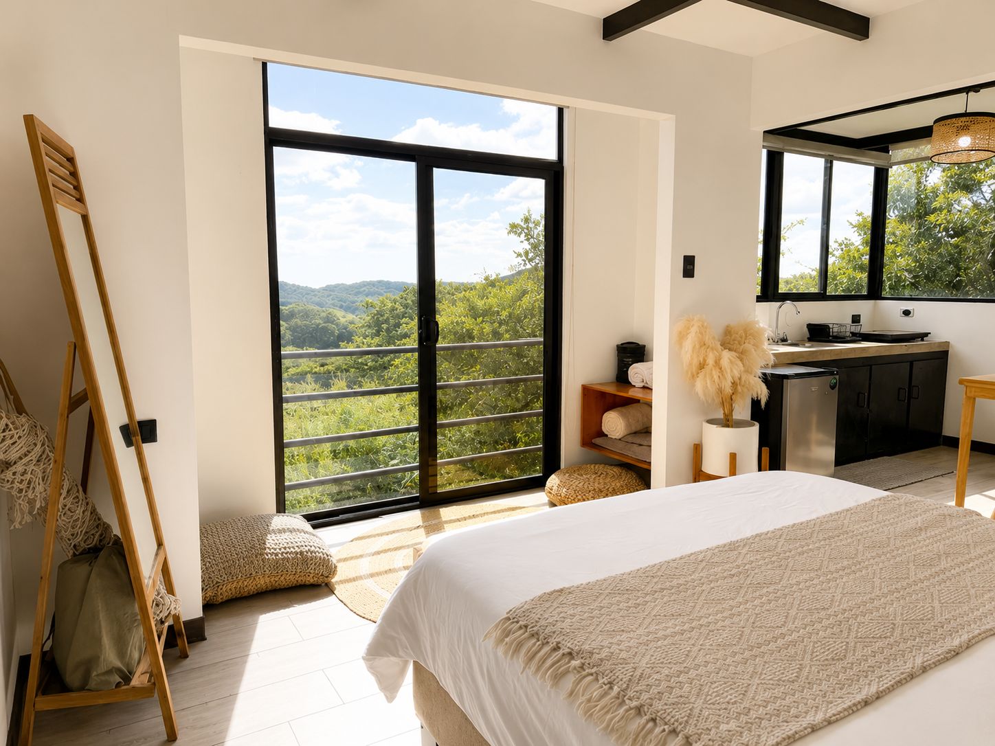 Ein Schlafzimmer mit großem Fenster, einem Bett, einem Nachttisch, einem Spiegel und einer Küchenzeile.
