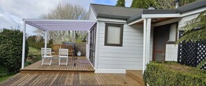 A single-story house with a deck, a covered patio, and a small garden.