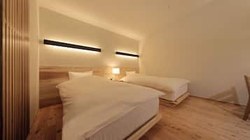Un dormitorio con dos camas, piso de madera e iluminación en la pared.