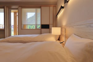 Habitación de hotel con una cama grande, una lámpara de noche y un ventanal con vistas al exterior.