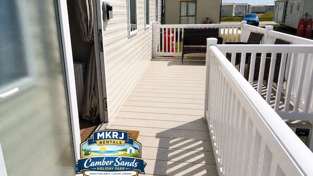 A deck leading to a mobile home with a white railing, a window, and a door.