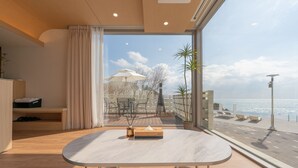 A modern room with a large window, a round table, and a view of the beach. - Ocean Bliss (Ulsan)