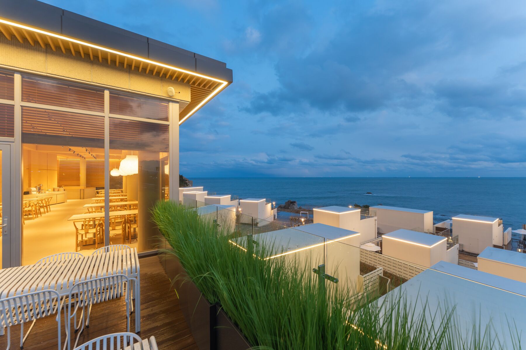 Una terrazza sul tetto con posti a sedere all'aperto, vista mare e un edificio moderno con ampie finestre.