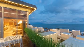 Una terrazza sul tetto con posti a sedere all'aperto, vista mare e un edificio moderno con ampie finestre.