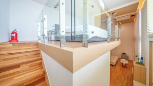 A modern interior with a glass-enclosed balcony, wooden flooring, and a visible fire extinguisher. - Ocean Bliss (Ulsan)