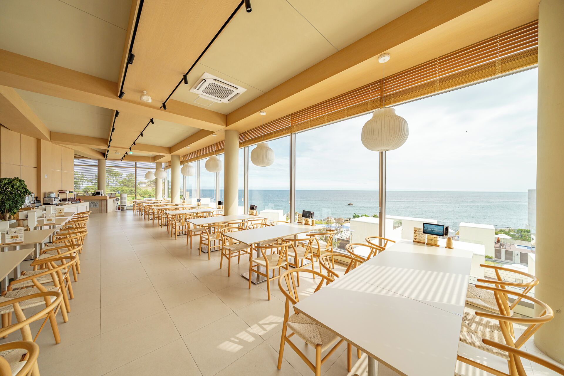 Un ristorante spazioso con soffitti alti, ampie finestre vista oceano e un design d'interni moderno.