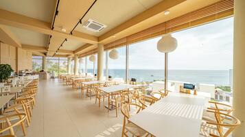 Un ristorante spazioso con soffitti alti, ampie finestre vista oceano e un design d'interni moderno.