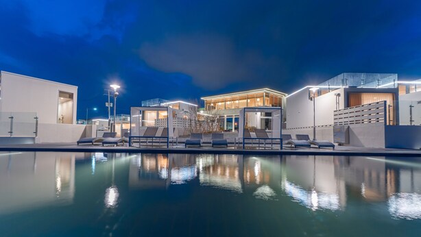 A modern hotel with a pool area, lounge chairs, and a well-lit building facade. - Ocean Bliss (Ulsan)