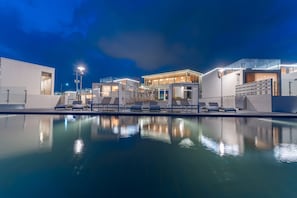 A modern hotel with a pool area, lounge chairs, and a well-lit building facade. - Ocean Bliss (Ulsan)