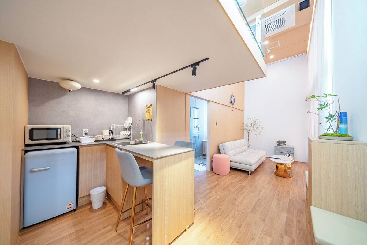 Una cocina compacta con microondas, lavabo y taburetes de bar.